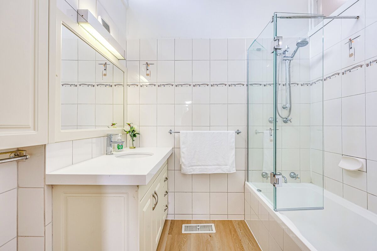 A bathroom with a glass-enclosed shower, a white sink, and a mirror above it.