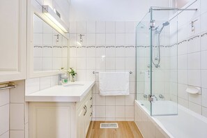 Une salle de bain avec une douche à parois de verre, un lavabo blanc et un miroir au-dessus.
