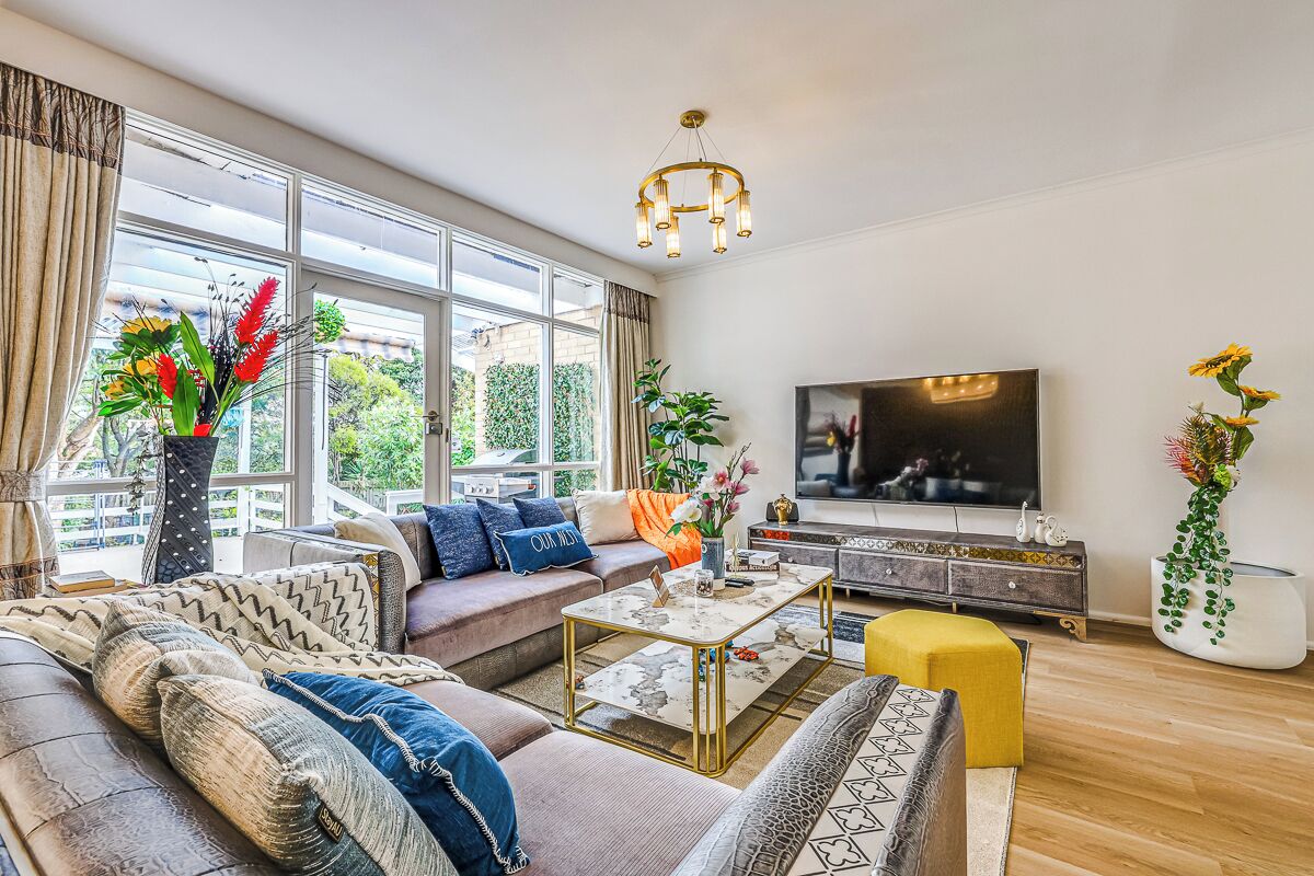 A modern living room with a sofa, coffee table, TV, and large windows.