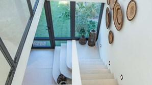 A modern interior with a staircase leading to a balcony, white walls, and decorative wooden plates. - Contemporary villa with heated pool, close to the town centre (STE MAXIME)