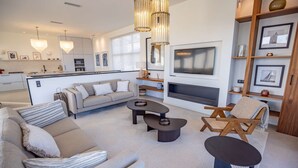 A modern living room with a sofa, coffee table, and armchair, a fireplace, and a kitchen in the background. - Contemporary villa with heated pool, close to the town centre (STE MAXIME)