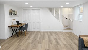 Une pièce spacieuse avec un bureau en bois, une chaise et un escalier menant à un autre niveau.