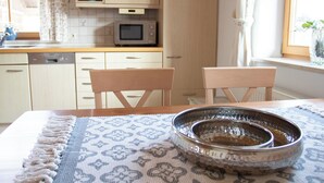 A kitchen with wooden cabinets, a microwave, and a window with curtains. - Vacation apartment with terrace, garden and lake view on the ground floor, for 2 to 3 pers. (Waging am See)