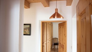 A hallway with wooden doors, a hanging pendant light, and a framed picture on the wall. - Vacation apartment with terrace, garden and lake view on the ground floor, for 2 to 3 pers. (Waging am See)