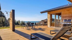 A wooden deck with outdoor furniture, a grill, and a view of the sea. - Sea to Sky Retreat by Manzanita Beach Getaway: Ocean Views, 3BR Hilltop Home (Nehalem)