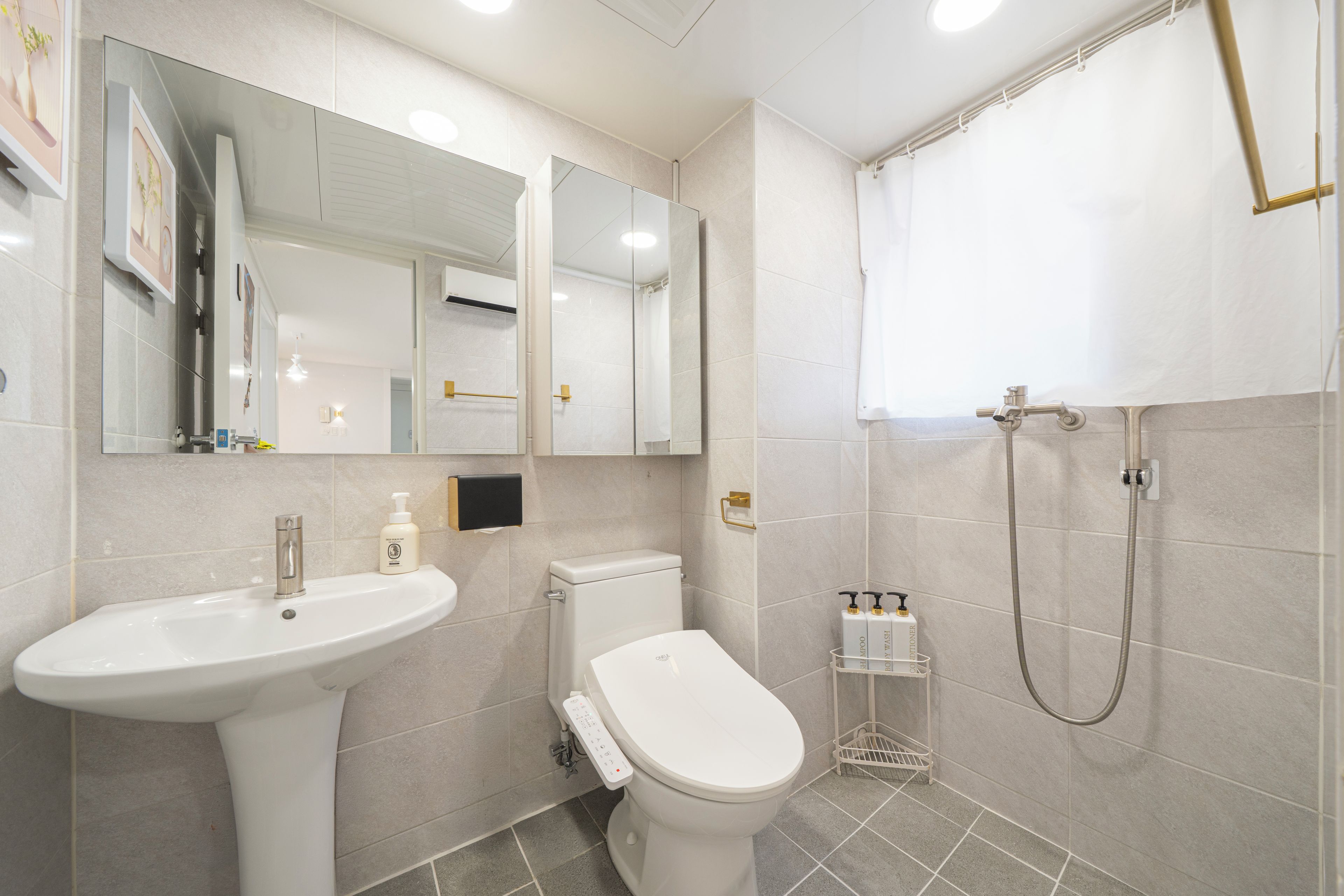 Un baño moderno con lavamanos, inodoro y ducha.