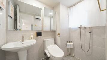 Un baño moderno con lavamanos, inodoro y ducha.