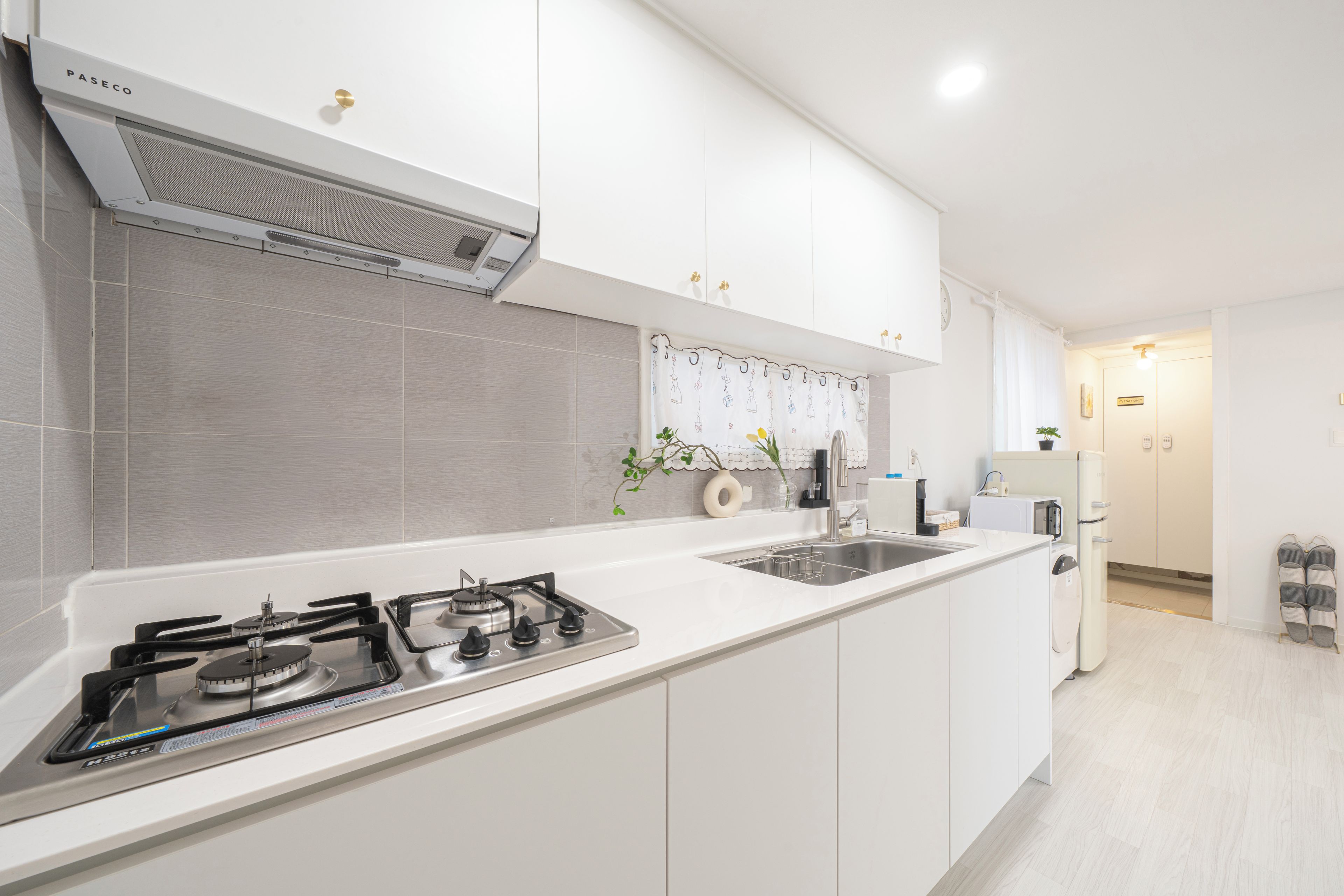 A modern kitchen with white cabinets, a gas stove, a microwave, and a built-in oven.