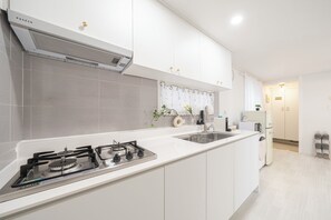 A modern kitchen with white cabinets, a gas stove, a microwave, and a built-in oven.