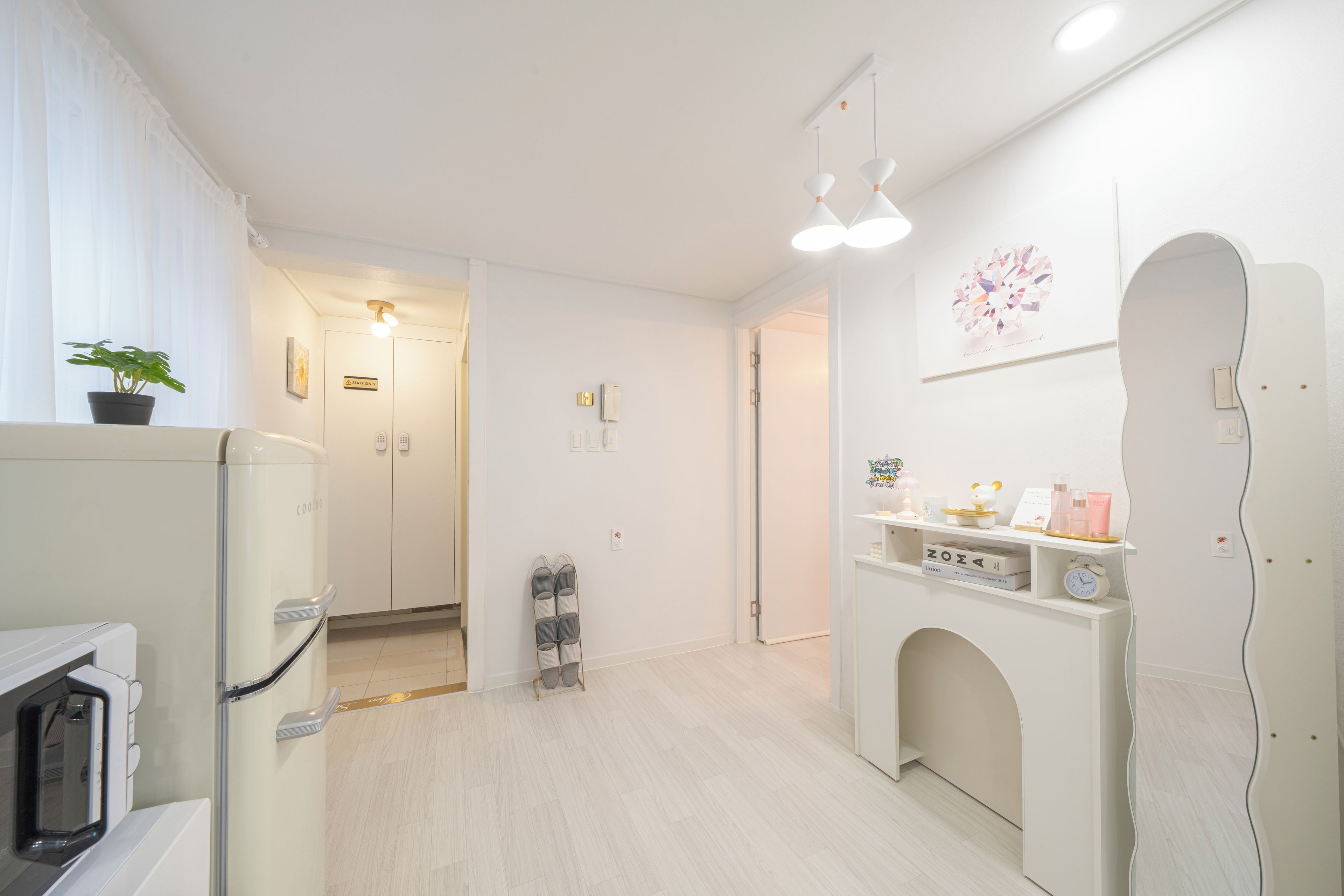A hotel room with a kitchenette, a small seating area, and a vanity with toiletries.