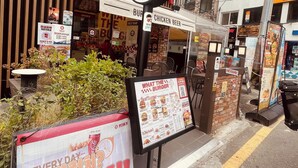 Ένα εστιατόριο με μπέργκερ, όπου μια πινακίδα υποδεικνύει ότι υπάρχει μπαρ με αυτοεξυπηρέτηση και προσφέρεται μια ποικιλία από μπύρες με γεύση κοτόπουλου.