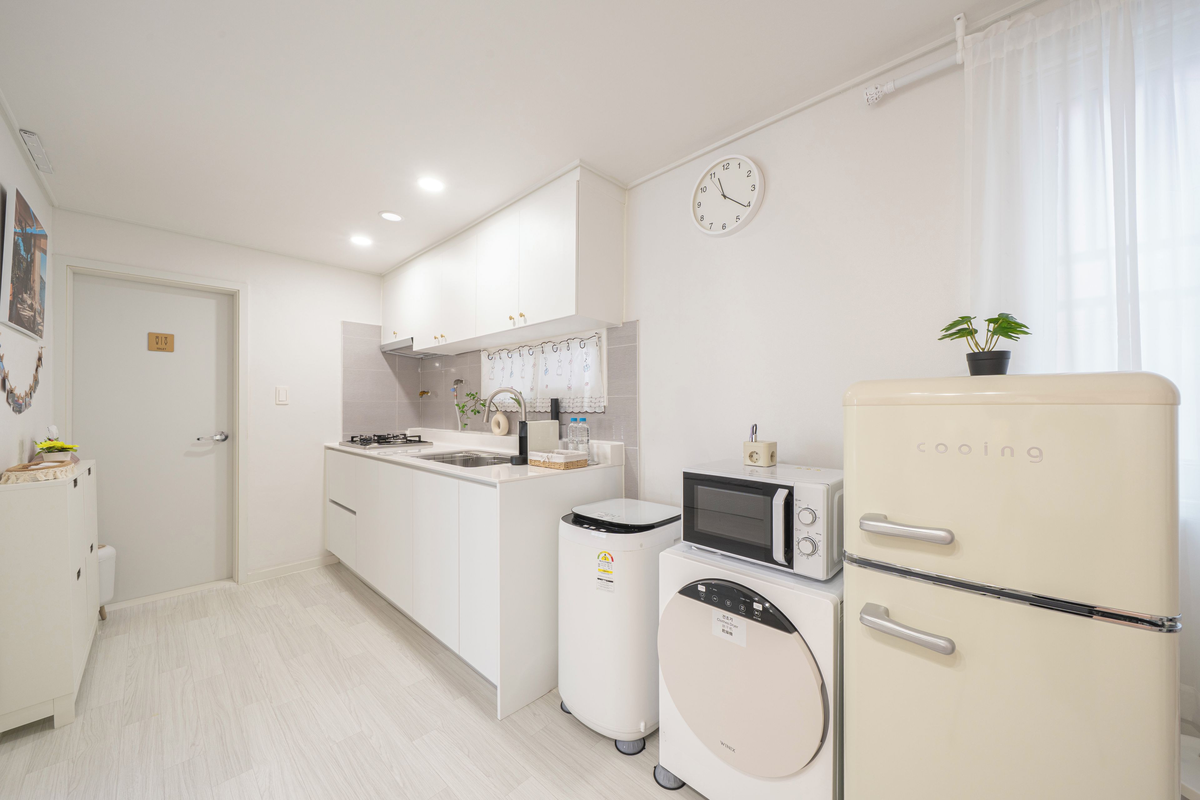 Una cocina compacta equipada con microondas, refrigerador y lavadora.