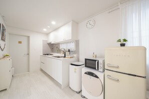A compact kitchen with a microwave, a refrigerator, and a washing machine. - Golden Stay (Busan)