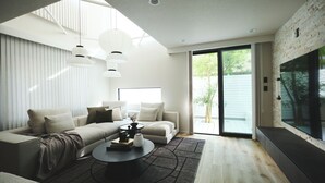 Uma sala de estar moderna com sofá, mesa de centro e luminárias pendentes.
