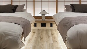 Quarto de hotel com duas camas, piso de madeira e parede com divisória japonesa tradicional shoji.