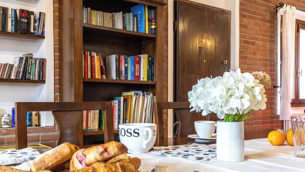 Une table accueillante, dressée pour le petit-déjeuner, avec des croissants, une tasse de café portant l’inscription « BOSS » et un vase de fleurs blanches.