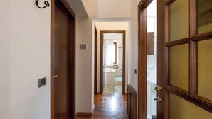 Un couloir avec des portes en bois et une vue sur une salle de bain équipée d’une baignoire et d’une douche.