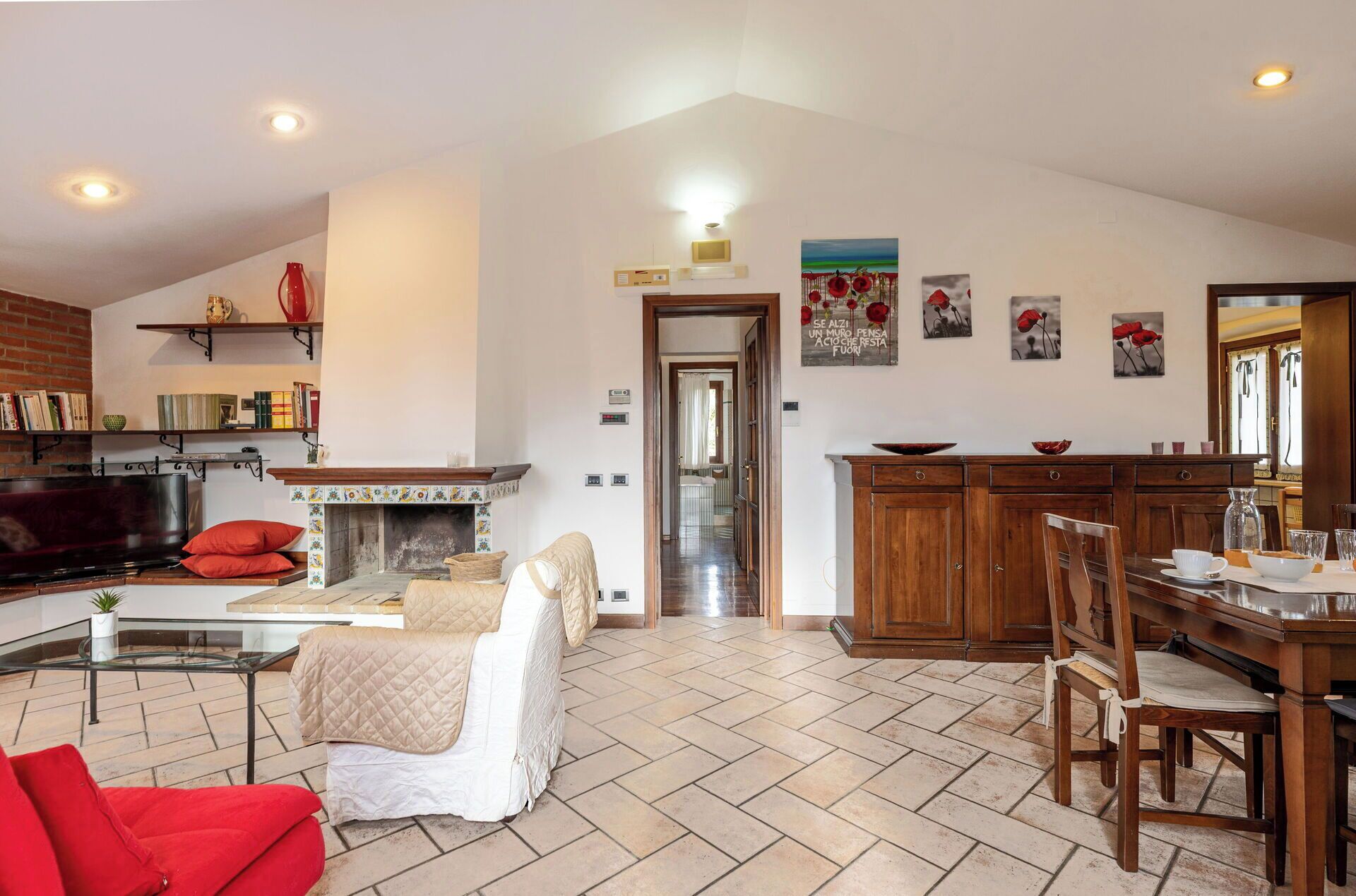Un salón amplio con chimenea, un comedor con armarios de madera y una cocina visible a través de un vano abierto.
