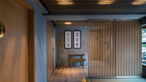 A hallway with wooden flooring, a bench, and two framed calligraphy pieces on the wall. - Oootopia - Tai Kok Tsui (Kowloon)