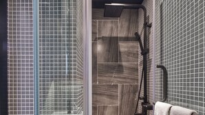 A modern bathroom with a glass shower enclosure, a rain showerhead, and a towel rack with a white towel. - Oootopia - Tai Kok Tsui (Kowloon)