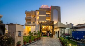 A hotel entrance with a sign, a covered walkway, and potted plants. - The Manthan Hotel - City View (Faizabad)