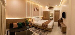 A modern hotel room with a bed, a sofa, a desk, and a TV. - The Manthan Hotel - City View (Faizabad)