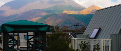 A building with a green roof, a staircase, and a view of mountains.