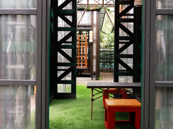 Un espace intérieur doté d’une surface verte en gazon synthétique, d’une table en bois et d’une structure métallique au motif quadrillé.