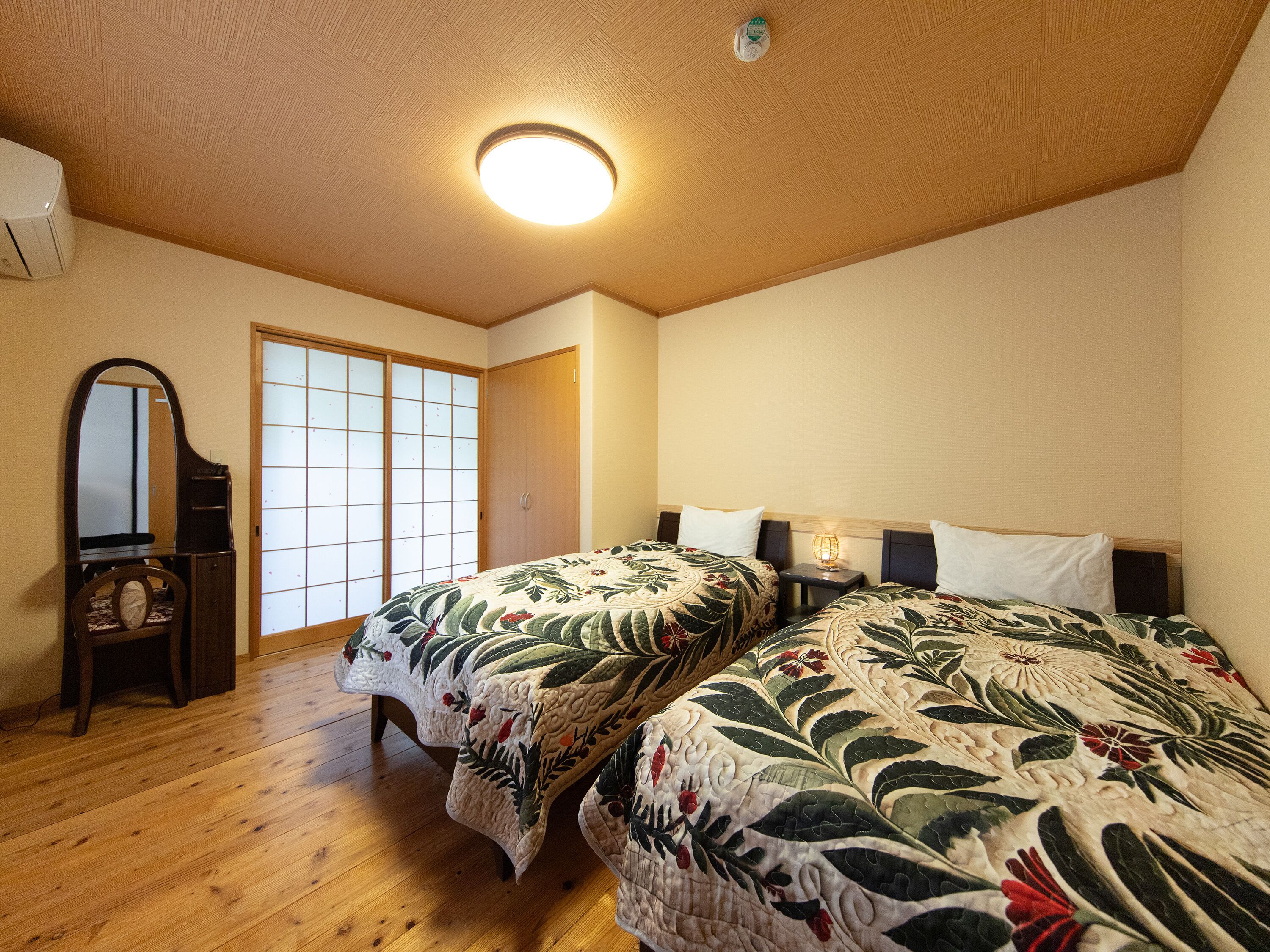 Un dormitorio con dos camas, techo de madera, un espejo y una puerta corredera.