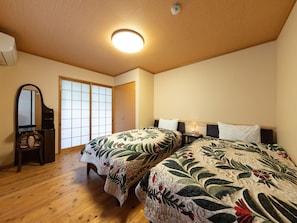 Une chambre avec deux lits, un plafond en bois, un miroir et une porte coulissante.