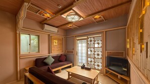 A cozy living room with a sofa, a coffee table, a TV, and a decorative screen door. - Yufuin Onsen 8A1 Yaeichi (Yufu)