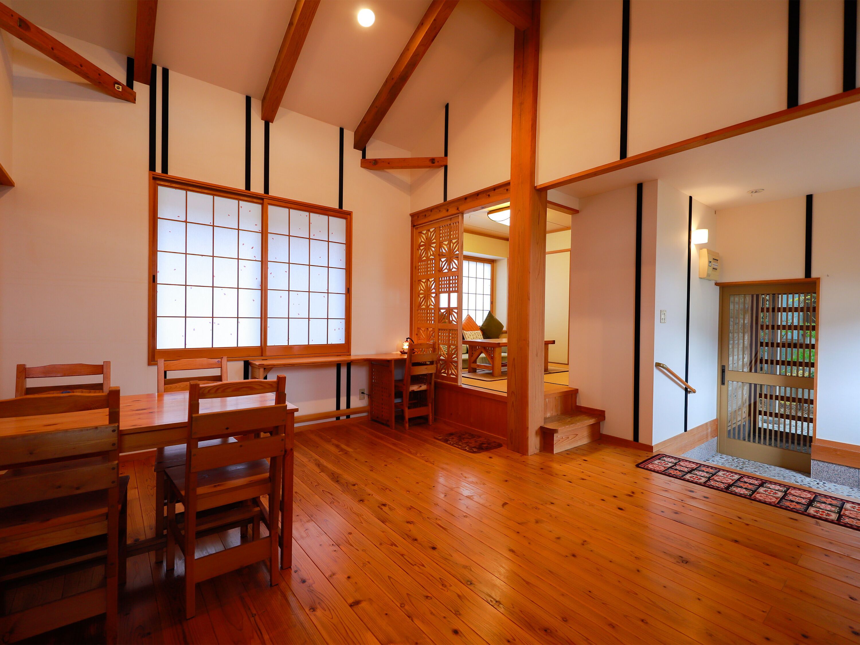 Una habitación japonesa tradicional con suelo de tatami, un biombó shoji y una mesa de madera con sillas.