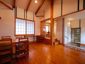 Une pièce de style japonais traditionnel, avec un sol recouvert de tatamis, un paravent en papier de riz (shoji) et une table en bois accompagnée de chaises.