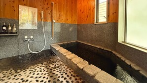 A wooden interior with a stone-tiled shower area and a small window. - Yufuin Onsen 8A1 Yaeichi (Yufu)