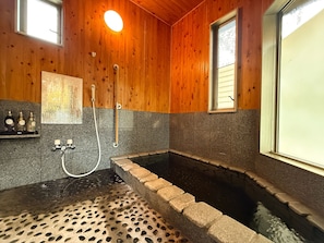 A wooden interior with a stone-tiled shower area and a small window. - Yufuin Onsen 8A1 Yaeichi (Yufu)