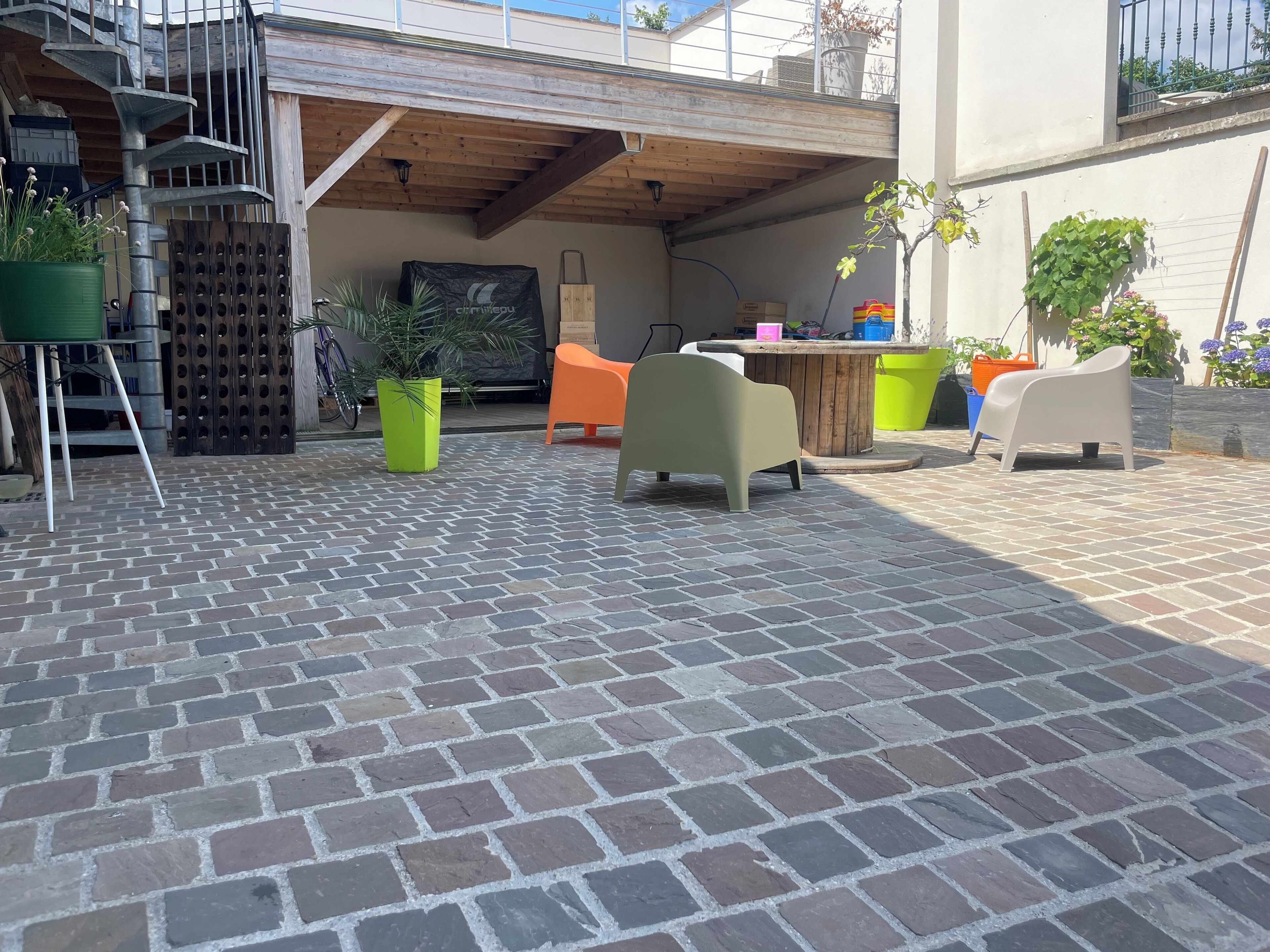 Une terrasse avec un sol en briques, un plafond en bois et du mobilier d’extérieur comprenant une chaise et une table.