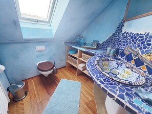 A bathroom with a skylight, a toilet, a sink with mosaic tiles, and a wooden floor. - Modern, well-maintained, and cozy vacation apartment in Donaustauf near Regensburg, 3.5 bedrooms (Donaustauf)