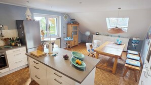 A modern kitchen with a central island, wooden cabinets, and a dining area with a table and chairs. - Modern, well-kept and cozy vacation apartment in Donaustauf near Regensburg 3 bedrooms (Donaustauf)