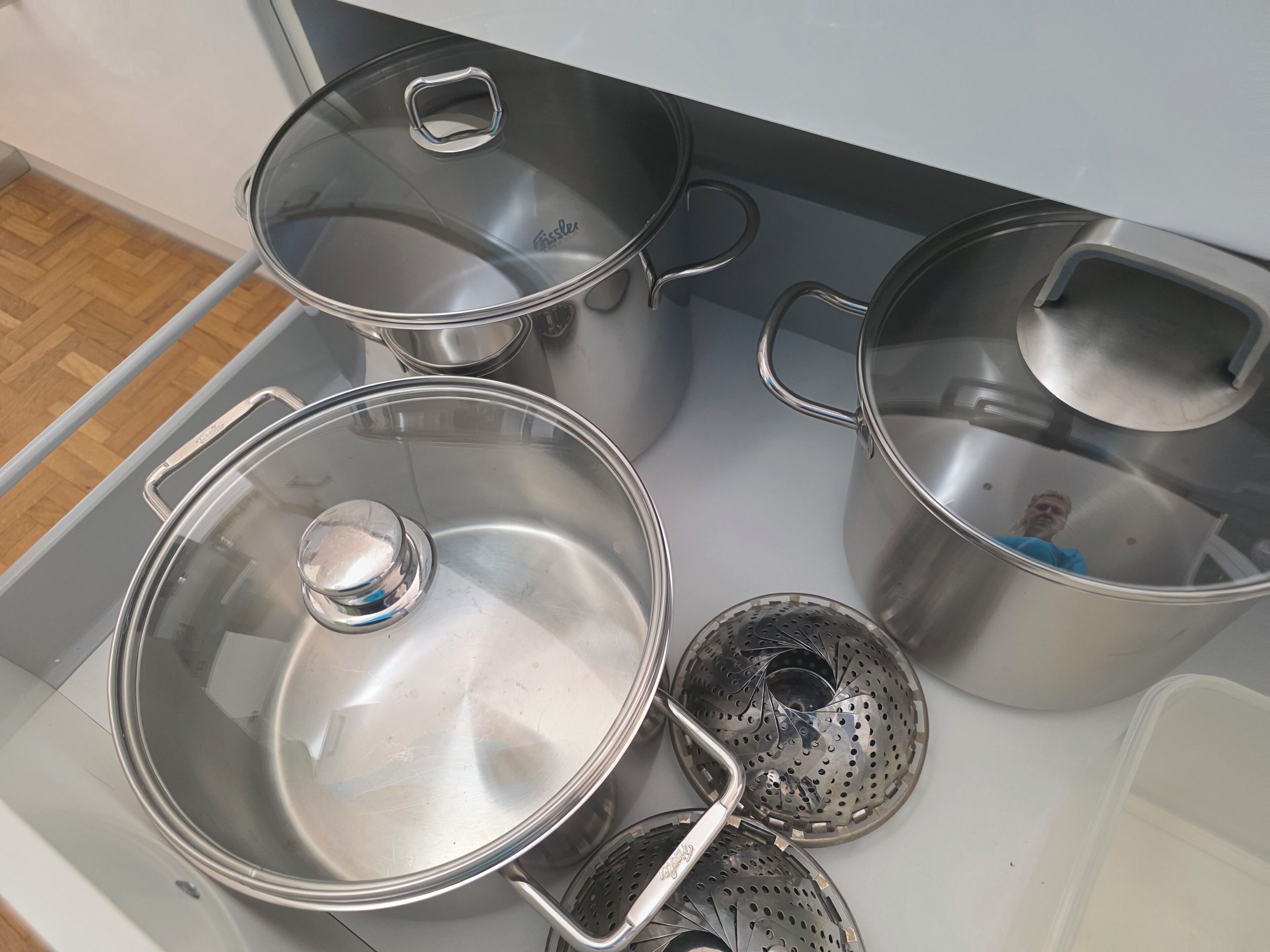 A kitchen with stainless steel pots and a colander.