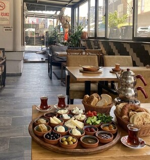 A dining area with a table set for a meal, including bread, cheese, olives, and a teapot. - Respiro Hotel Avcılar (İstanbul)