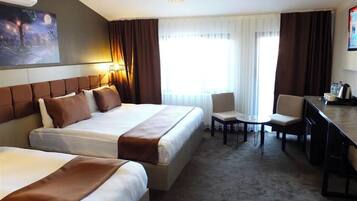 A hotel room with two beds, a desk, and a chair.