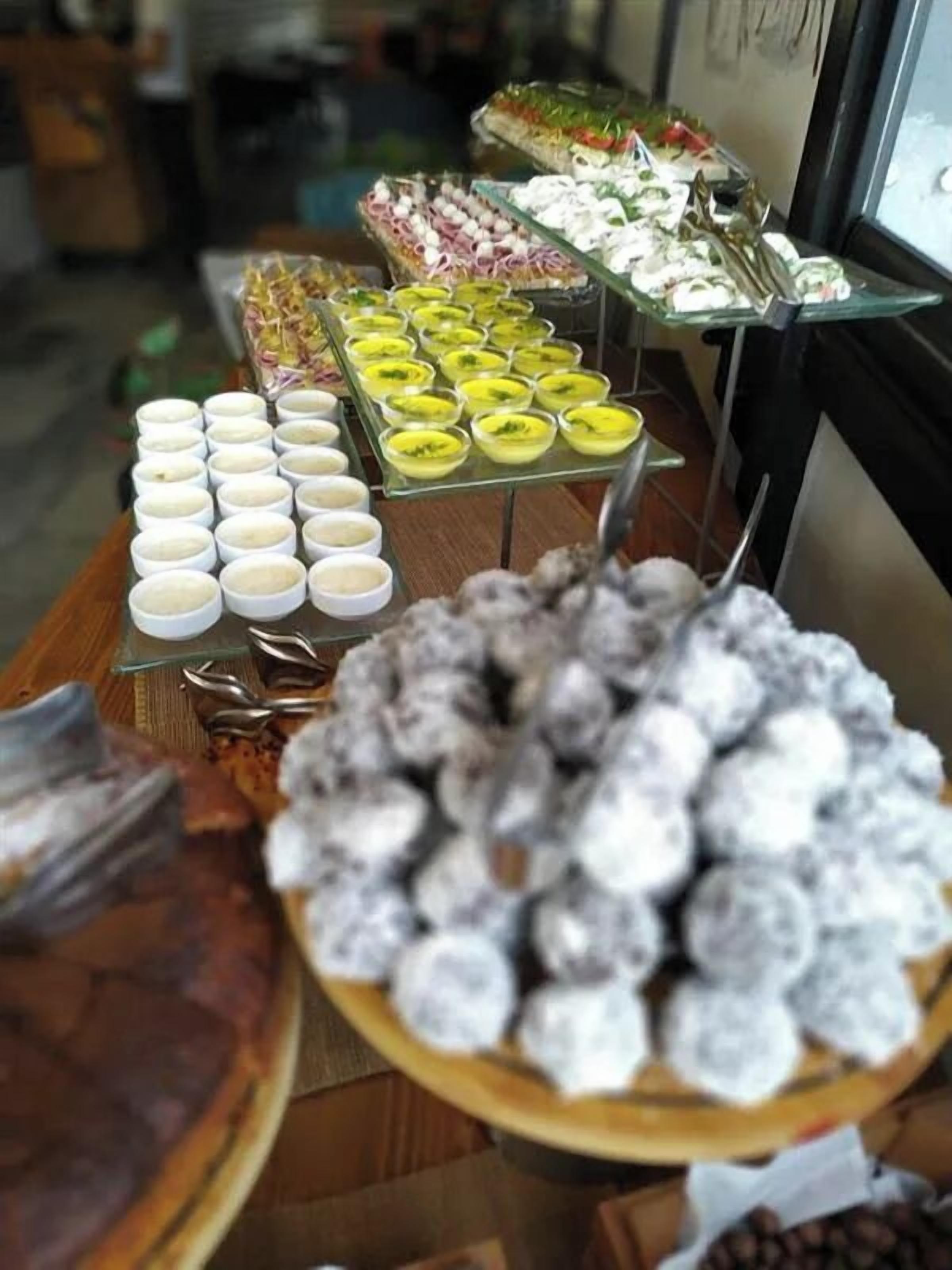 Un bufé con diversos platos, que incluyen postres y aperitivos, dispuestos en mesas.