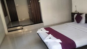 A modern hotel room with a large bed, a small desk, and a bathroom visible through an open door. - Hotel Saiba Lodging  (Paud)