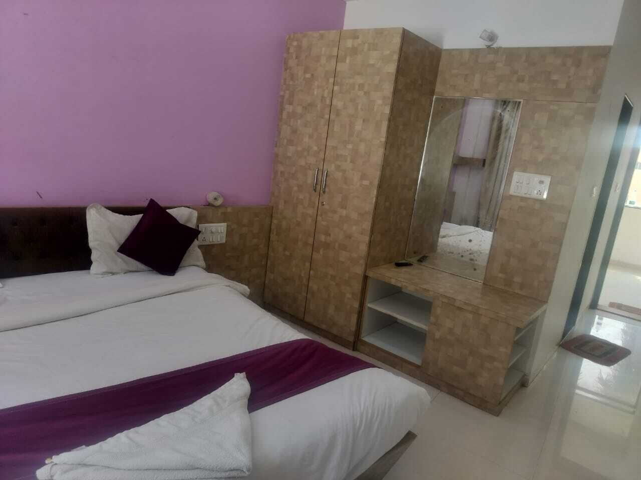 A hotel room with a large bed, a wardrobe, and a mirror.