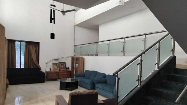 A spacious living area with a staircase, a blue sofa, a coffee table, and a wooden cabinet. - Hotel Saiba Lodging  (Paud)