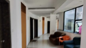 A modern hallway with a sofa and chairs, a large window, and a door. - Hotel Saiba Lodging  (Paud)