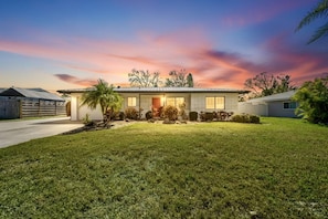 A single-story house with a well-maintained lawn, a front door, and a garage. - Sarasota 'Starburst' Home | Heated Pool | Dogs OK (Sarasota)