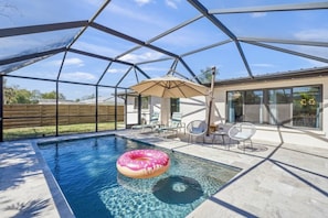 A swimming pool with a pink inflatable ring, surrounded by a covered patio area with chairs and a table. - Sarasota 'Starburst' Home | Heated Pool | Dogs OK (Sarasota)