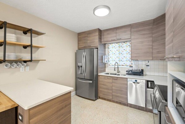 A modern kitchen with a stainless steel refrigerator, a dishwasher, and wooden cabinets. - Sarasota 'Starburst' Home | Heated Pool | Dogs OK (Sarasota)