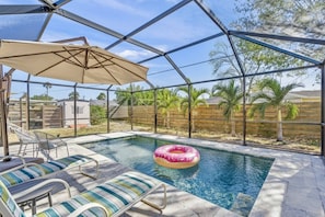 A covered outdoor swimming pool with lounge chairs and a floating ring. - Sarasota 'Starburst' Home | Heated Pool | Dogs OK (Sarasota)